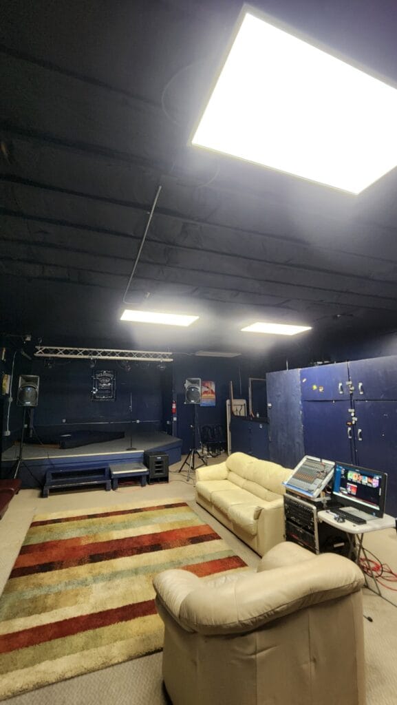 Wide view of rehearsal room with couches, mixer, and stage